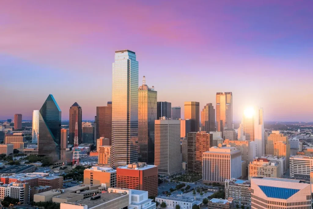 The Dallas, Texas city skyline against a blue sky at sunset