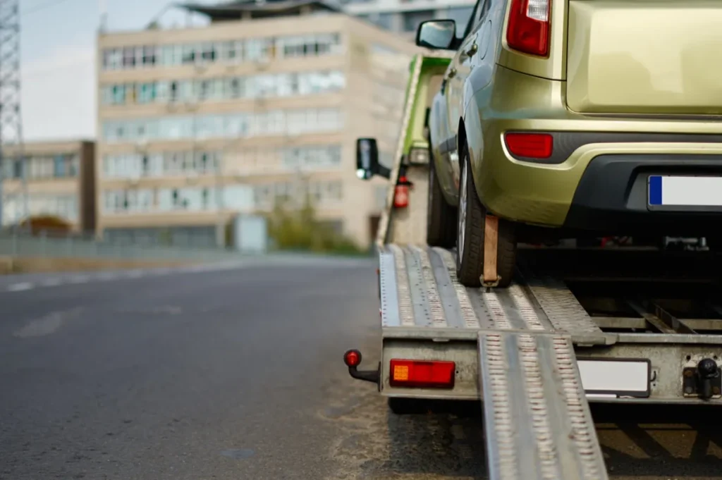 A non-running car secured on the deck of a flatbed tow truck ready for removal