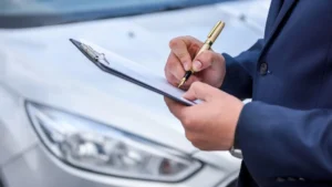 Vehicle seller reviewing an offer beside an older car and tow truck