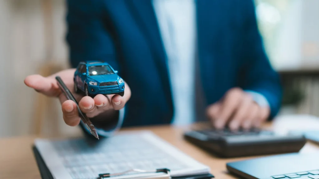 Vehicle seller reviewing an offer beside an older car and tow truck