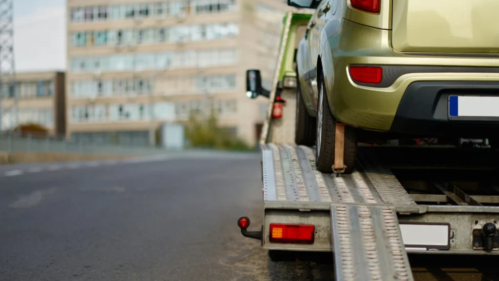 Professional flatbed truck collecting an older unwanted vehicle