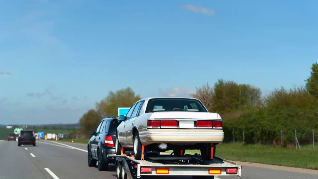 Professional flatbed truck collecting an older unwanted vehicle