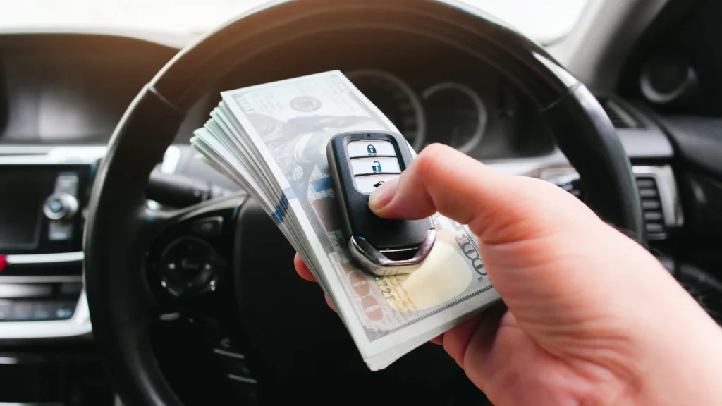 Vehicle seller reviewing an offer beside an older car and tow truck