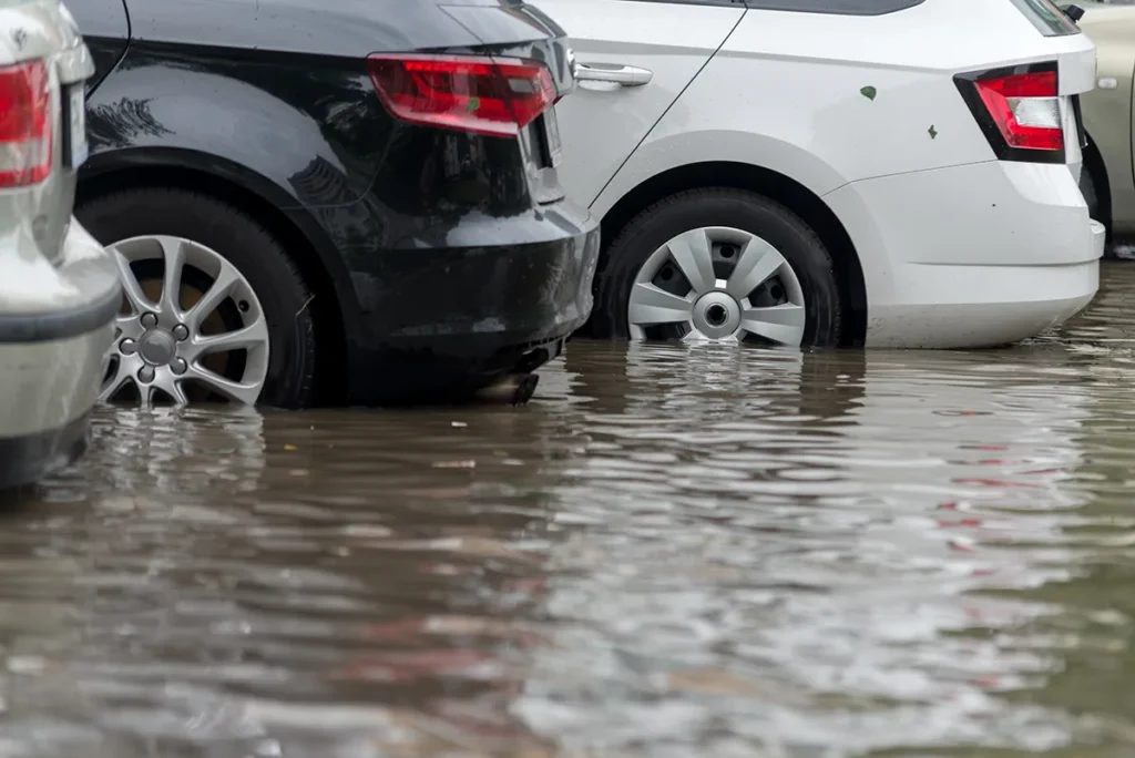 Cars standing in flood water with the water line visible at the wheels