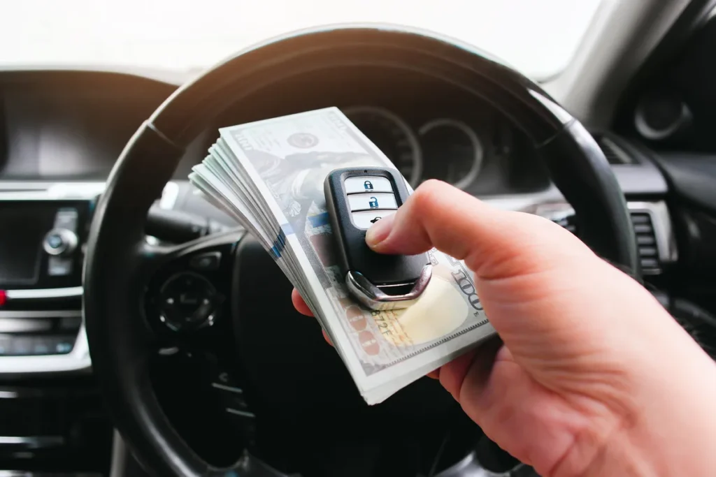 Car key and US dollar banknotes representing a junk car's cash value