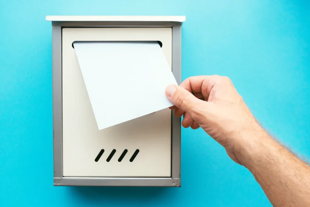 Hand placing an envelope into a mailbox to request a duplicate title