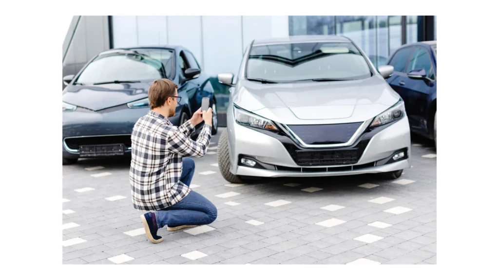 Man customer taking photo to mobile phone chooses auto and wants to buy new car in showroom
